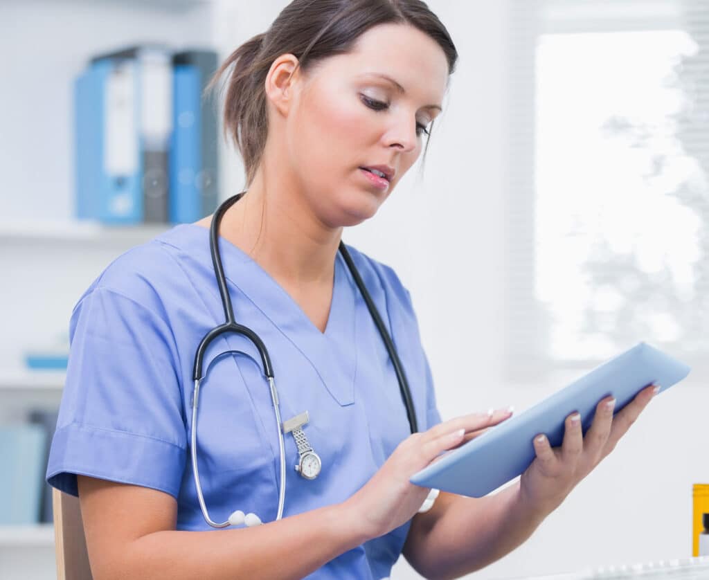Nurse using digital tablet in front of computer